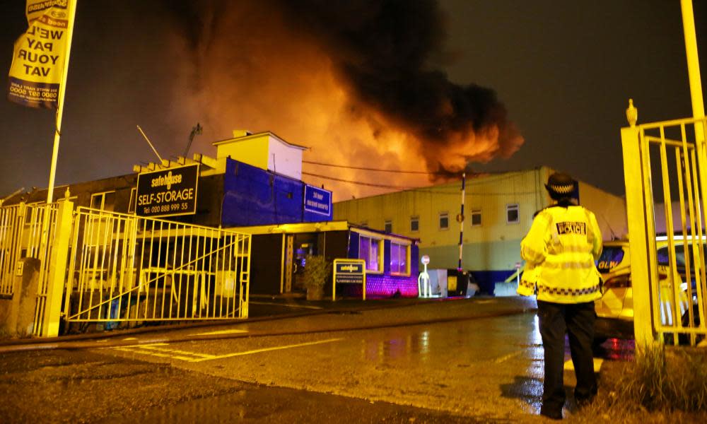 Police stand guard as firefighters (unseen) tackle a fire at a warehouse in Tottenham, north London. 