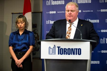 Toronto Mayor Rob Ford's wife Renata (L) puts her head down as her husband speaks at a news conference at City Hall in Toronto, November 14, 2013. REUTERS/Mark Blinch