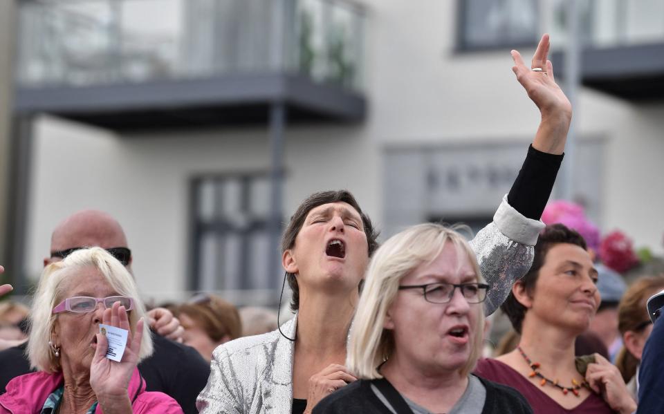 Members of the public sing along to 'Nothing Compares to You' before the hearse carrying Sinead O'Connor's coffin stops at her former home on the seafront on August 8, 2023 in Bray, Ireland. The public lined the streets of Bray today as the funeral cortËge of Sinead O'Connor passed through the town where she lived for 15 years. The iconic Irish singer known for her hit single "Nothing Compares 2 U" passed away at the age of 56 on July 26, 2023. O'Connor was renowned as a protest singer who used her fame to champion human rights, anti-racism, and expose injustice, particularly within the Catholic Church. She leaves behind three children.