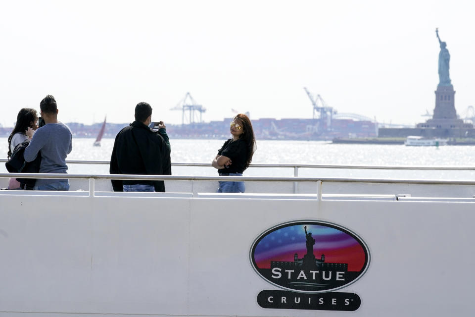 Visitors take photos after boarding the Statue of Liberty ferry, Tuesday, April 27, 2021, in New York. In recent weeks, tourism indicators for New York City like hotel occupancy and museum attendance that had fallen off a pandemic cliff have ticked up slightly. It's a welcome sight for a city where the industry has been decimated by the impact of the coronavirus. (AP Photo/Mary Altaffer)