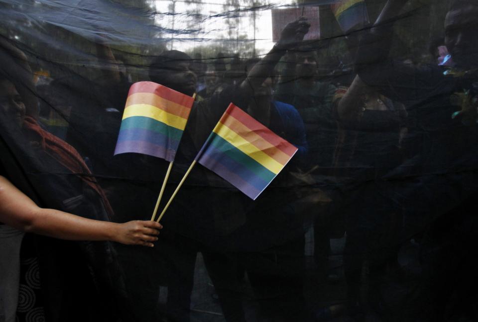 Gay rights activists hold black cloth and wave flags as they attend a protest against a verdict by the Supreme Court in New Delhi