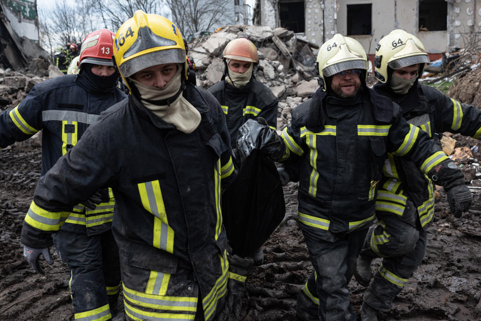 Rescue workers carry the body of a man who was found among the rubble of a destroyed apartment building in Borodianka, Ukraine, on April 9, 2022.