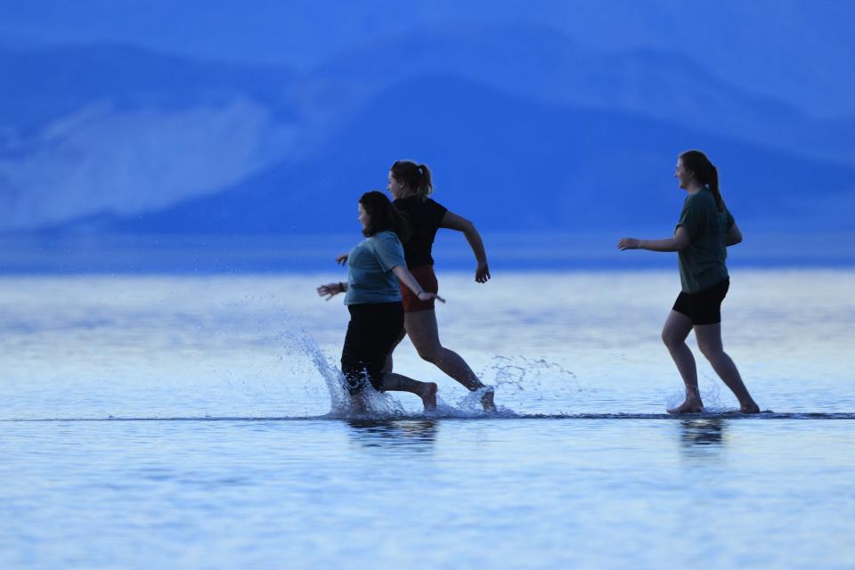 Tourists enjoy the rare opportunity to walk in water Sunday as they visit Badwater Basin, normally the driest place in the United States, in Death Valley National Park. The basin is the lowest point in North America, at 282 feet below sea level.