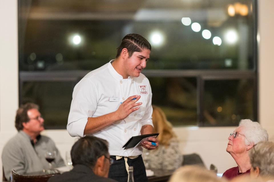 Student server Tony Campus takes a woman’s dinner order at Rancho Cielo.