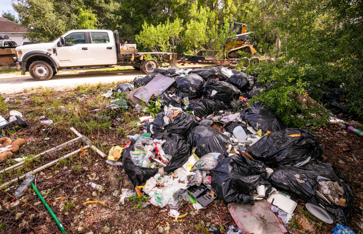 A vehicle makes its way by several illegally dumped bags of household garbage and other items in an empty lot near the corner of SE 102nd Terrace and SE 125th Lane on 125th Lane in Belleview on May 13.