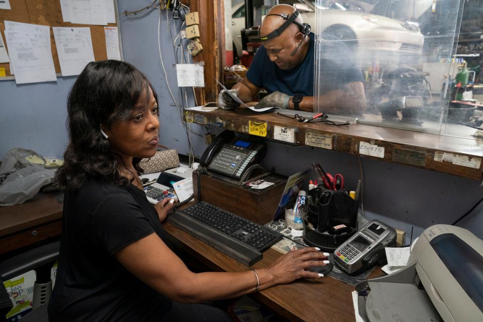 Earl "Butch" Hood Jr.  sticks his head through the office window as his wife Karon Hood works on a client's order at their shop Hood's Car Care Clinic in Detroit Friday, June 24, 2022.