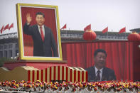 Participants cheer beneath a large portrait of Chinese President Xi Jinping during a parade to commemorate the 70th anniversary of the founding of Communist China in Beijing, Tuesday, Oct. 1, 2019. Trucks carrying weapons including a nuclear-armed missile designed to evade U.S. defenses rumbled through Beijing as the Communist Party celebrated its 70th anniversary in power with a parade Tuesday that showcased China's ambition as a rising global force. (AP Photo/Mark Schiefelbein)