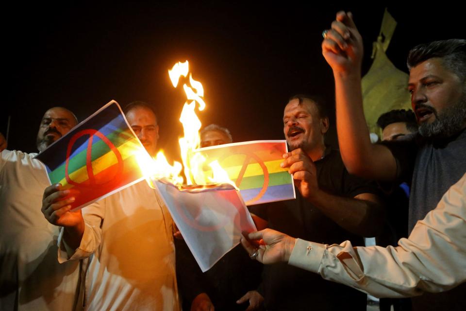 Supporters of Iraqi Shiite cleric Muqtada al-Sadr burn posters depicting an LGBTQ+ flag during a protest in Karbala, Iraq, June 29, 2023, sparked by the burning of a Quran in Sweden. / Credit: MOHAMMED SAWAF/AFP/Getty