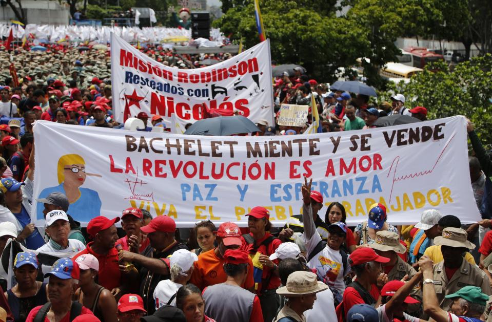Supporters of President Nicolas Maduro holds up a banner with a message that reads in Spanish: "Bachelet lies and sold herself. The revolution is love, peace and hope," during a protest against a report by Michelle Bachelet, U.N. high commissioner for human rights, in Caracas, Venezuela, Saturday, July 13, 2019. Bachelet recently published a report accusing Venezuelan officials of human rights abuses, including extrajudicial killings and measures to erode democratic institutions. (AP Photo/Leonardo Fernandez)