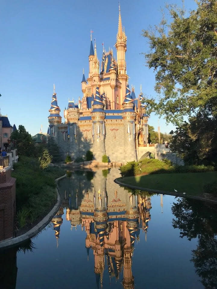 El castillo de Cenicienta reflejado en el agua en el Reino Mágico de Walt Disney.