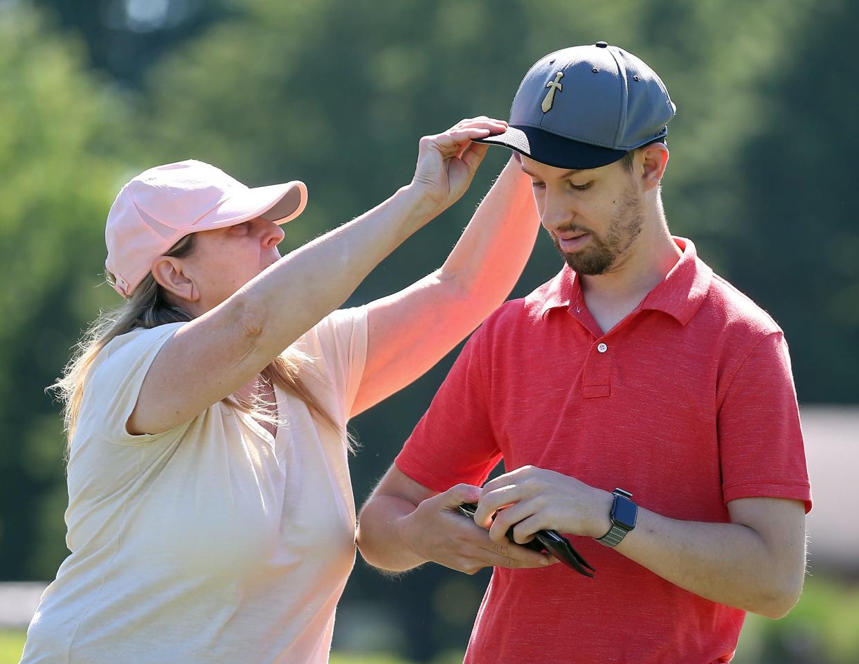Paulette Gaia, left, adjusts her son Jeremy's cap at Firestone Country Club on Tuesday.