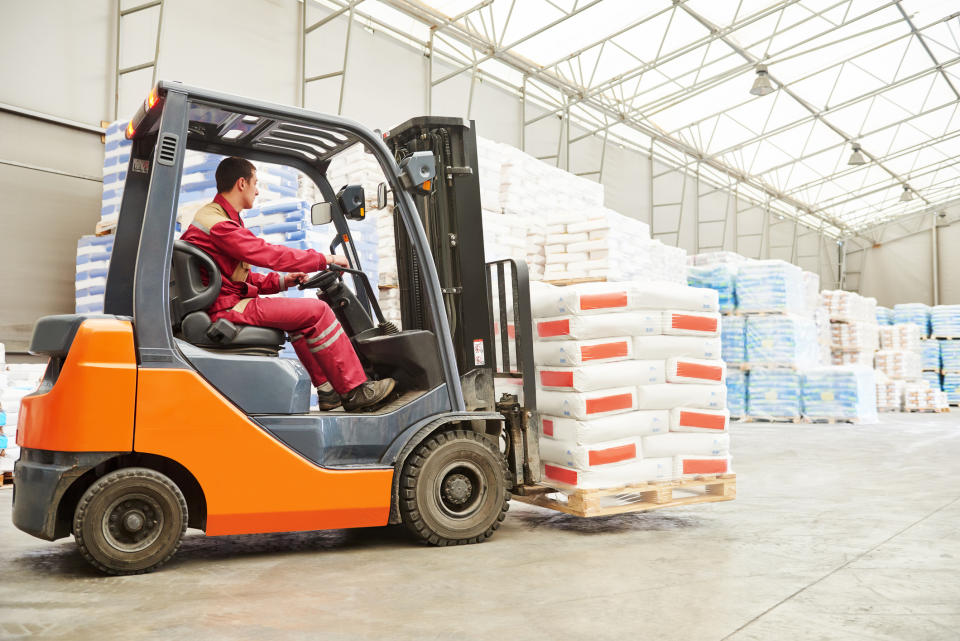 A man drives a forklift in a warehouse