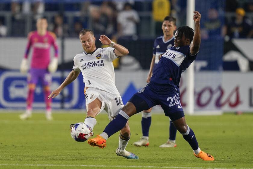 Vancouver Whitecaps forward Levonte Johnson (28) and Los Angeles Galaxy midfielder Oriol Rosell (16) vie for the ball during the second half of an MLS soccer match, Sunday, July 30, 2023, in Carson, Calif. (AP Photo/Ryan Sun)