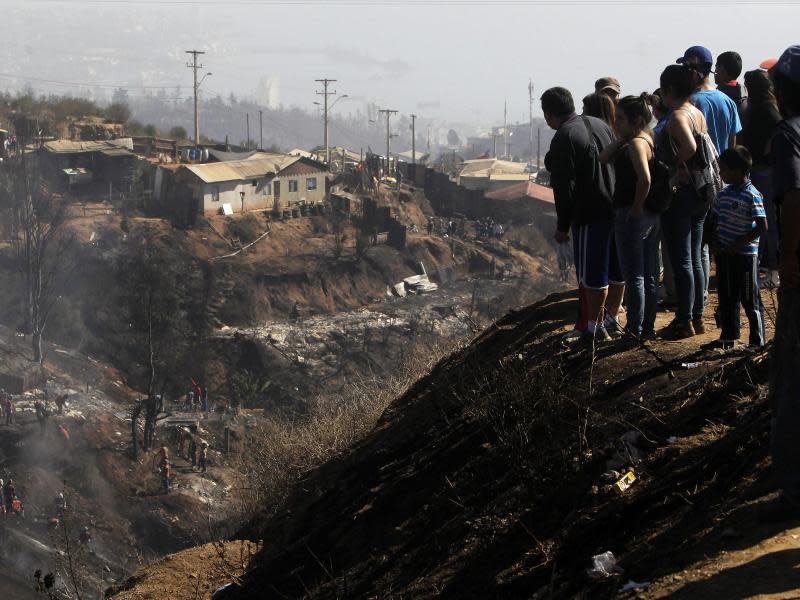 Fassungslos betrachenh Anwohner die vom Feuer hinterlassene Trümmerlandschaft. Foto: Felipe Trueba