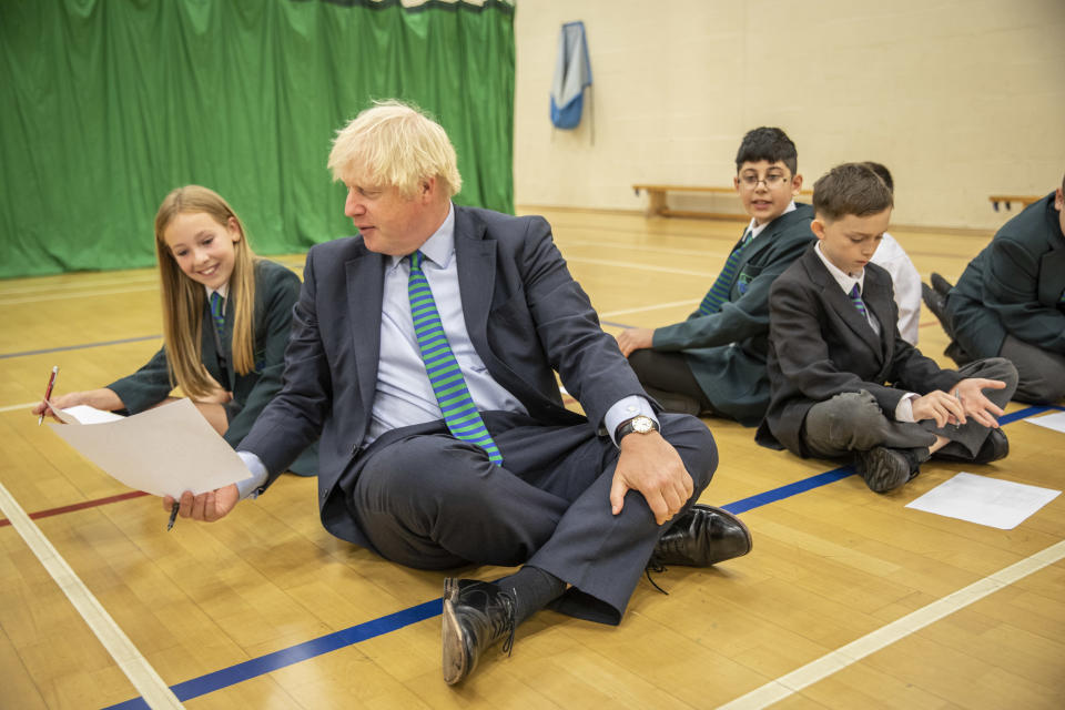 COALVILLE, ENGLAND  - AUGUST 26: British Prime Minister Boris Johnson, wearing the school tie he was presented with on arrival, takes part in a getting to know you induction session in the gym with year 7 pupils on their first day back at school during a visit to Castle Rock school on August 26, 2020 in Coalville, United Kingdom. (Photo by Jack Hill - WPA Pool/ Getty Images)