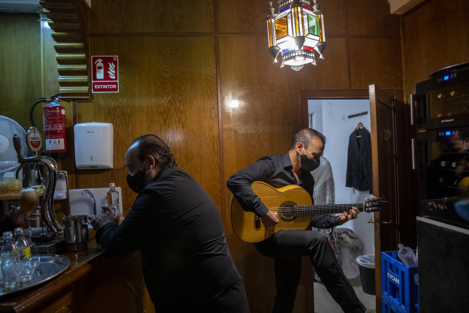 Flamenco guitarist Jose Sison tunes his guitar next to flamenco singer Antonio 'El Pola' rehearsing before taking part in a flamenco show at the Torres Bermejas "tablao," or live flamenco venue, in Madrid, Spain, Friday, Sept. 25, 2020. The passion and drama of live flamenco shows are back on stage in Madrid. But now the performers are behind Perspex screens and keeping their distance from the audience. The Torres Bermejas “tablao,” or live flamenco venue, has reopened its doors to customers after seven months closed due to the COVID-19 pandemic. (AP Photo/Manu Fernandez)