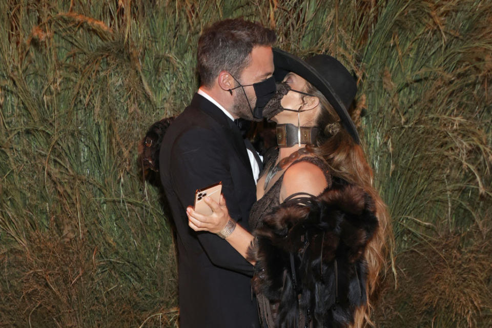 A close up of Ben Affleck and Jennifer Lopez kissing with face masks on