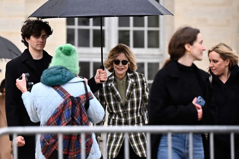 Meg Ryan luego del desfile de Loewe durante la Semana de la Moda en París. La actriz, un ícono de las comedias románticas de los 90, saludó al público con una gran sonrisa. Debajo del paraguas que la cobijó de la fina lluvia que cayó en la capital francesa, la estrella lució un blazer a cuadros, un pantalón ancho de terciopelo y una camisa. ¿La paleta de colores elegida? Verde, blanco y negro. Completó el look con botas negras, cartera y lentes de sol