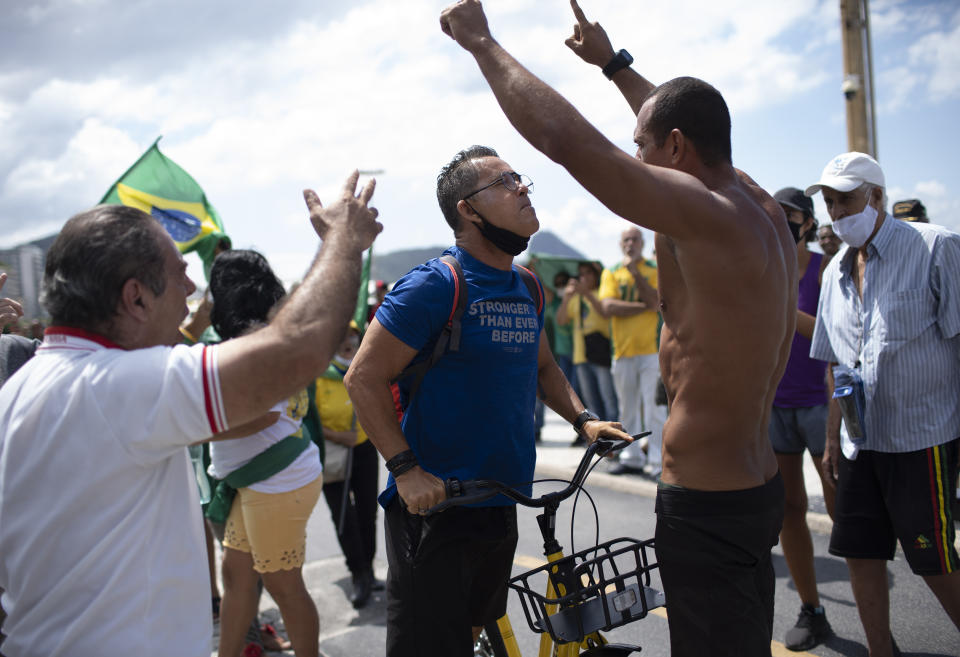 An opponent, center left, confronts supporters of Brazilian President Jair Bolsonaro during a demonstration supporting Bolsonaro after leaders of all three branches of the armed forces jointly resigned following the replacement of the defense minister, on Copacabana beach in Rio de Janeiro, Brazil, Wednesday, March 31, 2021. (AP Photo/Silvia Izquierdo)