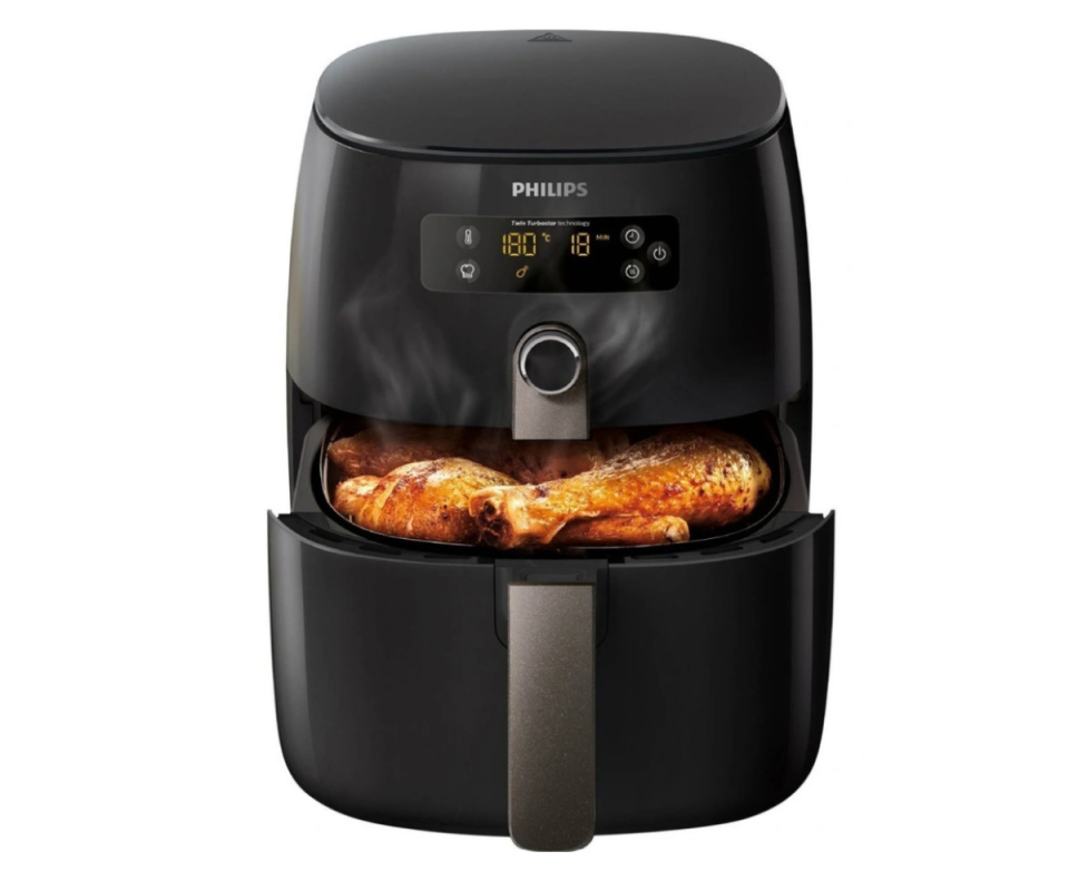 A black air fryer against a white background with the drawer open showing a roast chicken.