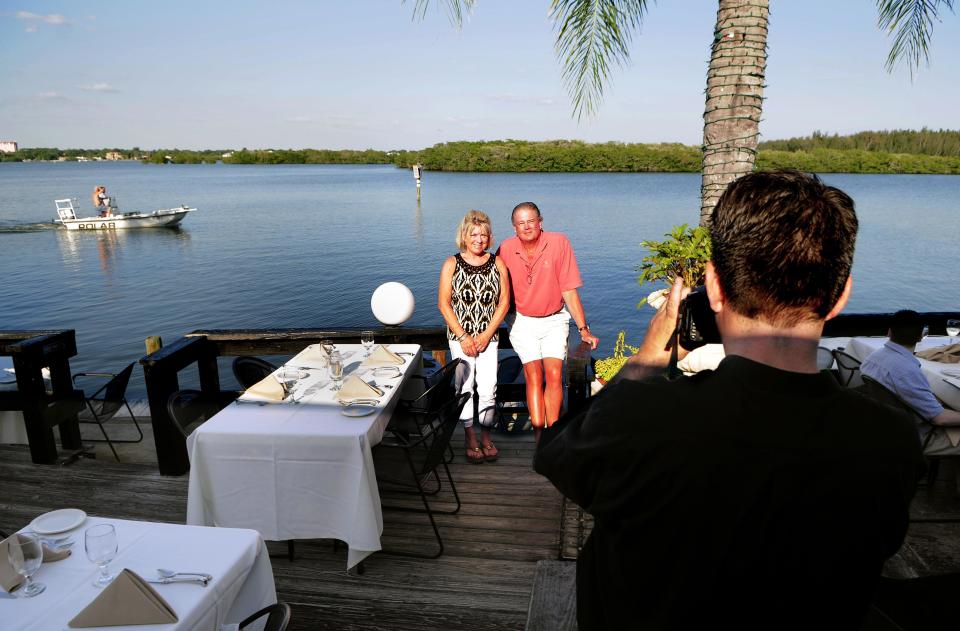 Wendy and Jeff Birtch, on vacation from Buffalo, New York, get their picture taken while dining at Ophelia's on the Bay restaurant at Siesta Key.