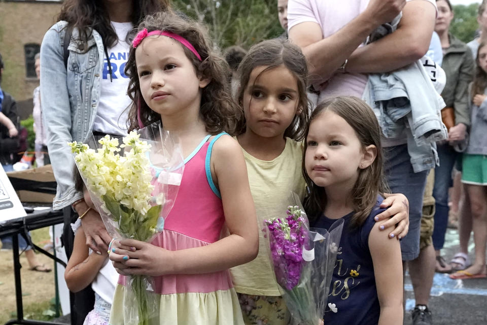 Three young girls hold flowers and listen during a vigil in Highwood, Ill., for the victims of Monday's Highland Park., Ill., Fourth of July parade, Wednesday, July 6, 2022. (AP Photo/Charles Rex Arbogast)