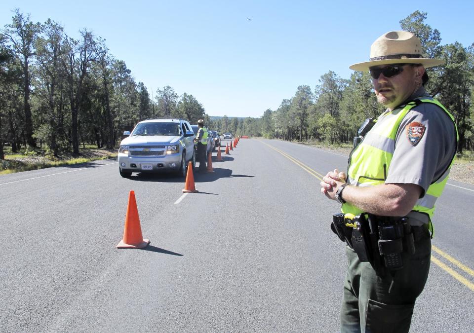 Grand Canyon National Park Ranger Jason Morris surveys traffic backed up at the closed park entrance on Thursday, Oct. 3, 2013 in Ariz. More than 400 national parks are closed as Congress remains deadlocked over federal government funding. (AP Photo/Brian Skoloff)