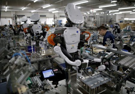 FILE PHOTO: Humanoid robots work side by side with employees in the assembly line at a factory of Glory Ltd., a manufacturer of automatic change dispensers, in Kazo, north of Tokyo, Japan, July 1, 2015. REUTERS/Issei Kato/File Photo