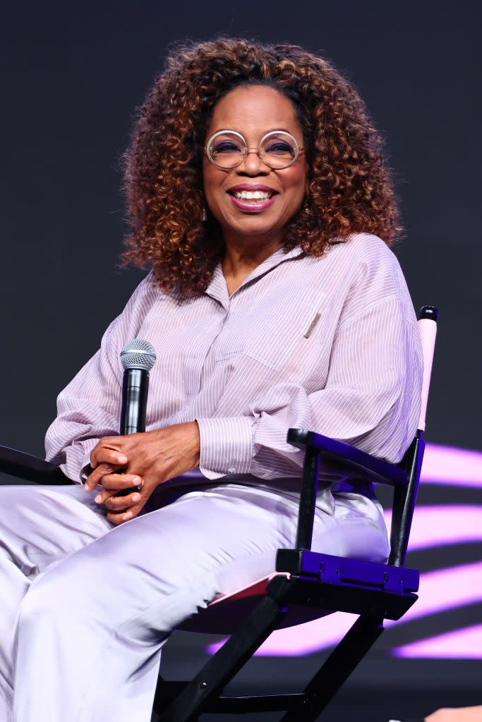 oprah winfrey pictured smiling sitting on stage with a microphone