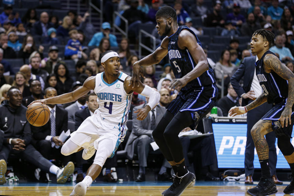 Charlotte Hornets guard Devonte' Graham, left, drives around Orlando Magic center Mo Bamba as Orlando Magic guard Markelle Fultz looks on in the first half of an NBA basketball game in Charlotte, N.C., Monday, Jan. 20, 2020. (AP Photo/Nell Redmond)