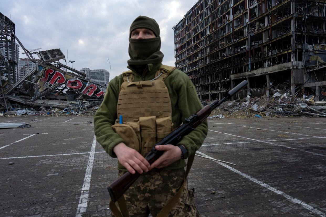 A soldier stands guard amid the destruction from shelling of a shopping center in Kyiv, Ukraine, on March 30, 2022.