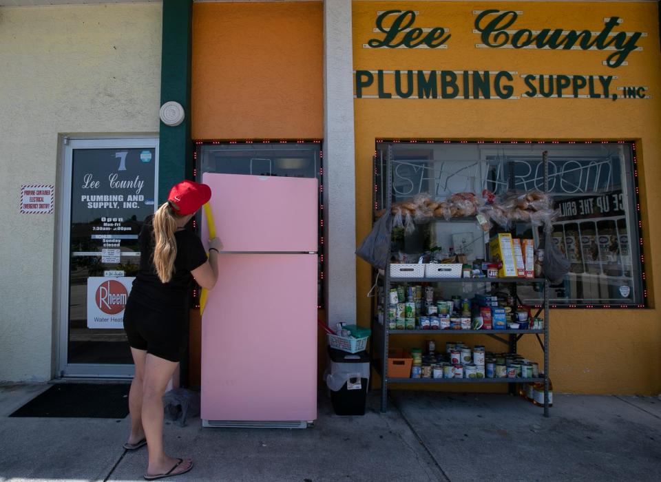 Katie Seaver, 31, of Cape Coral, helps restore a refrigerator being used as a food supply for local residents. Dionne Lopez who runs Lee County Plumbing & Supply, started a community fridge in November of 2020, before Thanksgiving, to help Cape Coral residents who were suffering because of the pandemic.Ê