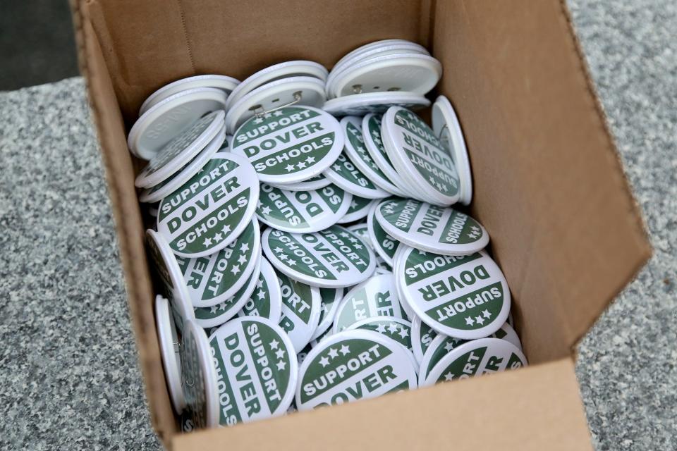 The Dover Teachers Union provides buttons during a rally to support the school budget at Henry Law Park Wednesday, May 4, 2022.