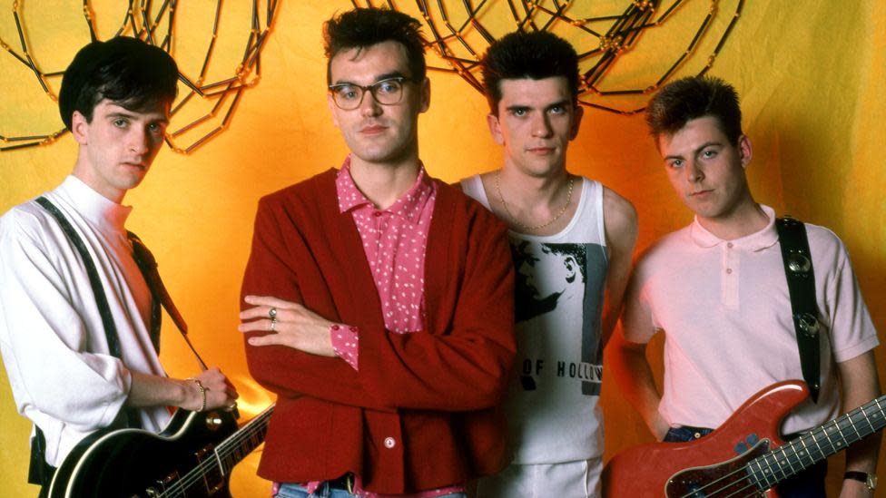 The Smiths' guitarist Johnny Marr, in a white shirt, singer Morrissey, in glasses and a pink and white spotted shirt and a red cardigan, drummer Mike Joyce, in a white vest, and bassist Andy Rourke, in a pink polo shirt pose for a portrait before their first show in Detroit during the 1985 Meat Is Murder Tour 