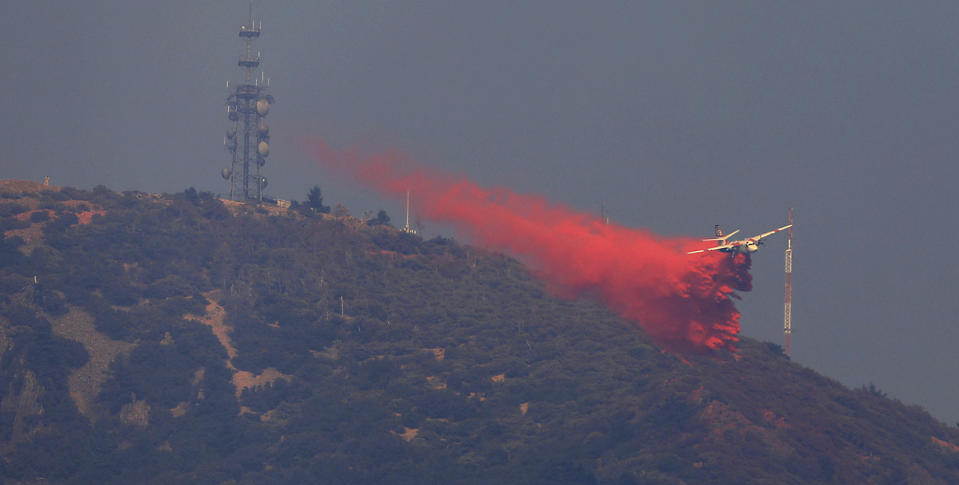 FILE- In this Oct. 13, 2017, file photo a Cal Fire tanker is used to create a retardant box on the north peak of California's Mt. St. Helena, to protect critical communication infrastructure. Oct. 13, 2017 As California counties face the prospect of increased utility power shut-off meant to prevent wildfires, counties with more resources are adapting much more easily to the challenge than poorer ones. (Kent Porter/The Press Democrat via AP)