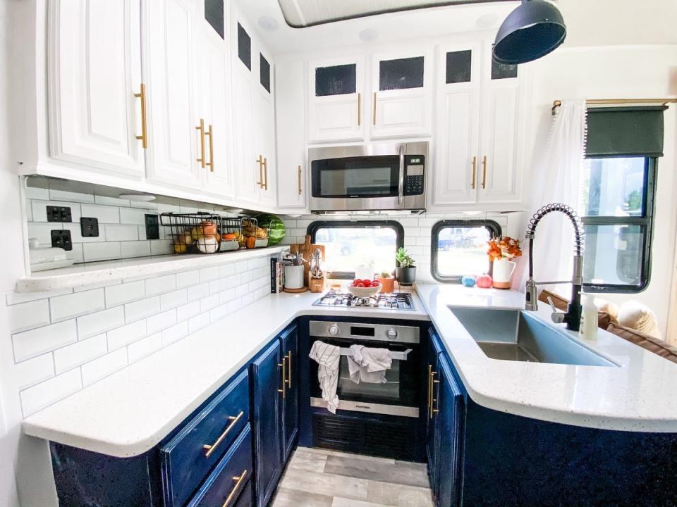 The kitchen with blue and white cabinets inside the Proha RV