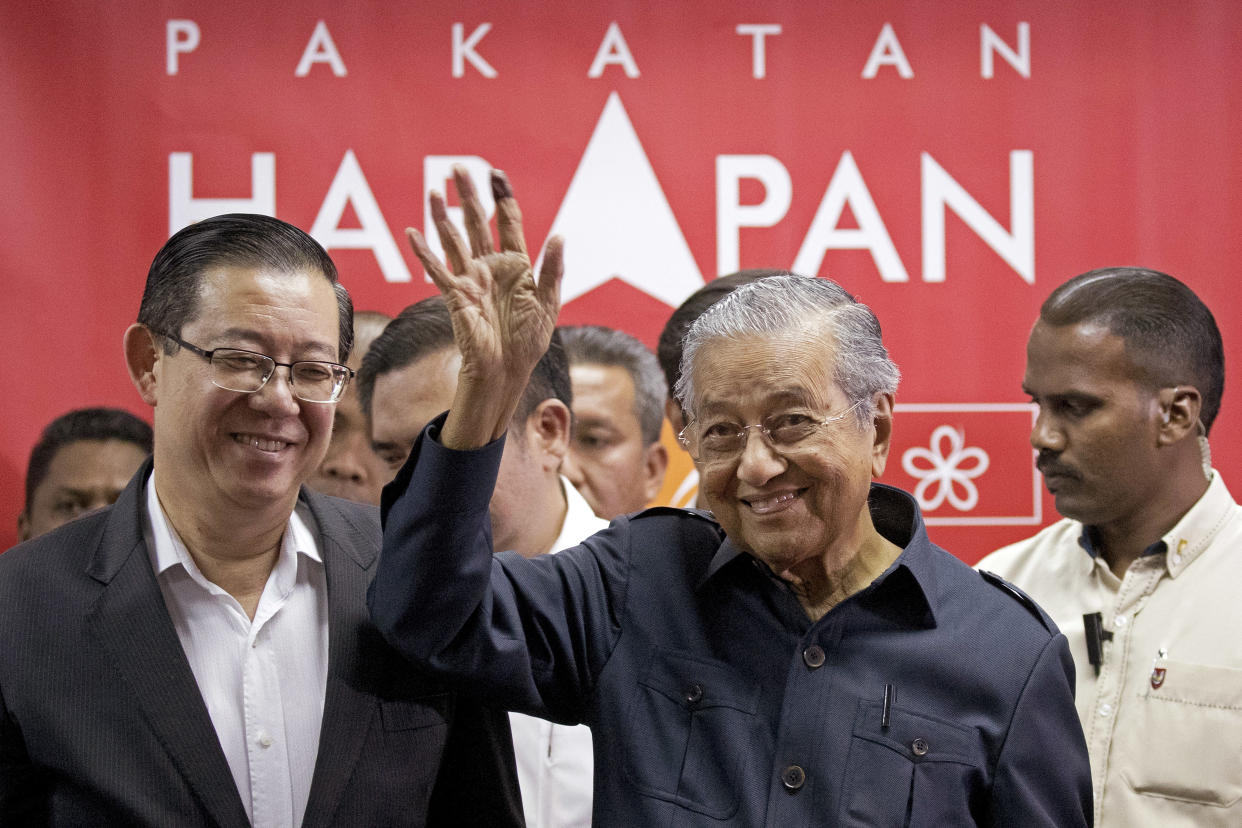 Malaysia’s Prime Minister Mahathir Mohamad, centre, waves next to newly-appointed Finance Minister Lim Guan Eng in Petaling Jaya on Saturday, 12 May. (AP Photo/Andy Wong)