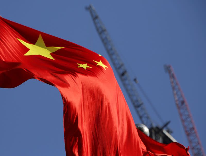 China's national flag is seen in front of cranes on a construction site at a commercial district in Beijing