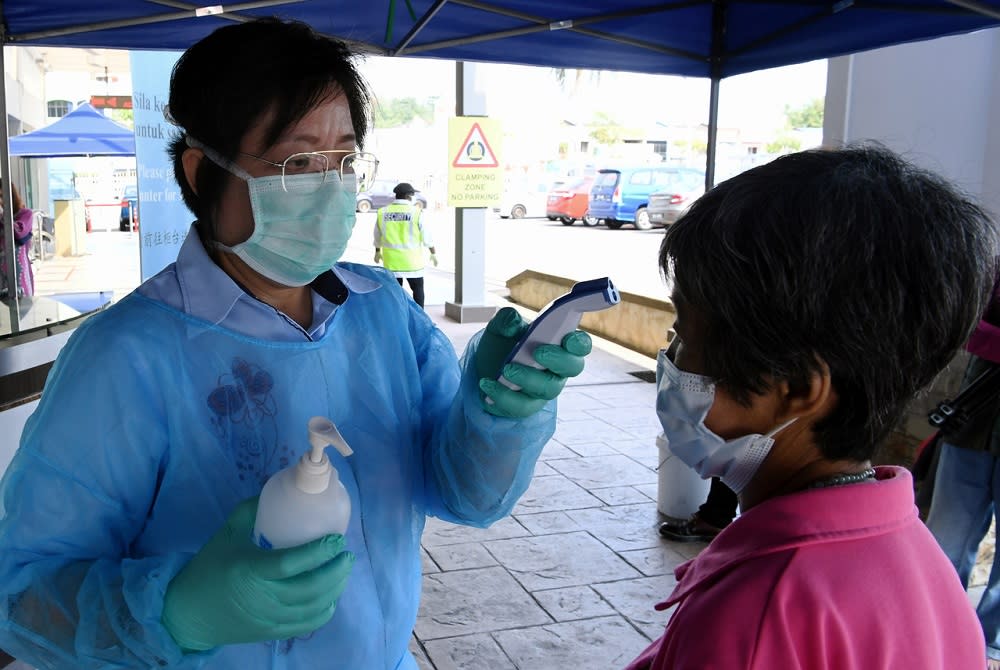A health worker from Mawar Medical Centre checks the temperature of a visitor in Seremban March 20, 2020. — Bernama pic