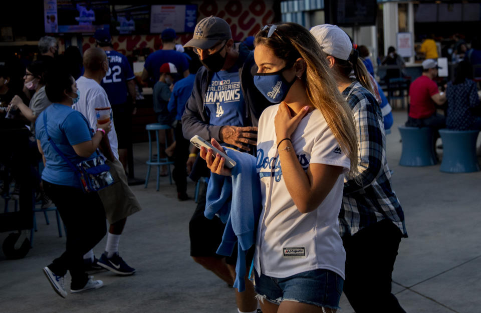 LOS ANGELES, CA - AUGUST 20, 2021: Masked Dodger fans walk in the concourse behind the outfield to get to their seats as tonight is the beginning of a new LA County health mandate requiring venues with more than 10,000 people to require masks at Dodger Stadium on August 20, 2021 in Los Angeles, California.(Gina Ferazzi / Los Angeles Times via Getty Images)