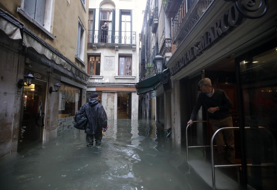 A man makes his way through water in Venice, Italy, Friday, Nov. 15, 2019. Waters are rising in Venice where the tide is reaching exceptional levels just three days after the Italian lagoon city experienced its worst flooding in more than 50 years. (AP Photo/Luca Bruno)