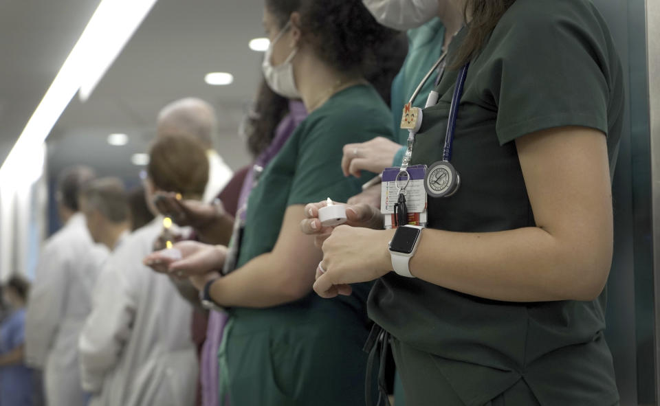 Doctors and nurses hold candles as they silently line the hospital hallway to pay tribute to the body of Maurice “Mo” Miller at NYU Langone Health in New York on Wednesday, Sept. 13, 2023. For a history-making 61 days and despite a brief rejection blip, a pig’s kidney worked normally inside his brain-dead body. (AP Photo/Shelby Lum)