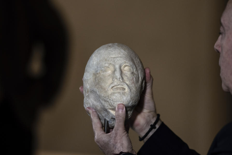 FILE - Acropolis Museum Director Nikolaos Stampolidis holds a marble head of a bearded man, one of three fragments from the ancient Parthenon temple that have been returned to Greece by the Vatican museums, in Athens, Friday, March 24, 2023. Italy, a long time victim of antiquities theft that has worked for decades to recover its treasures, is coming to terms with the fact that it, too has stolen loot in its museum collections: the relics of a brutal colonial empire that the country hasn't fully reckoned with. (AP Photo/Petros Giannakouris, File)
