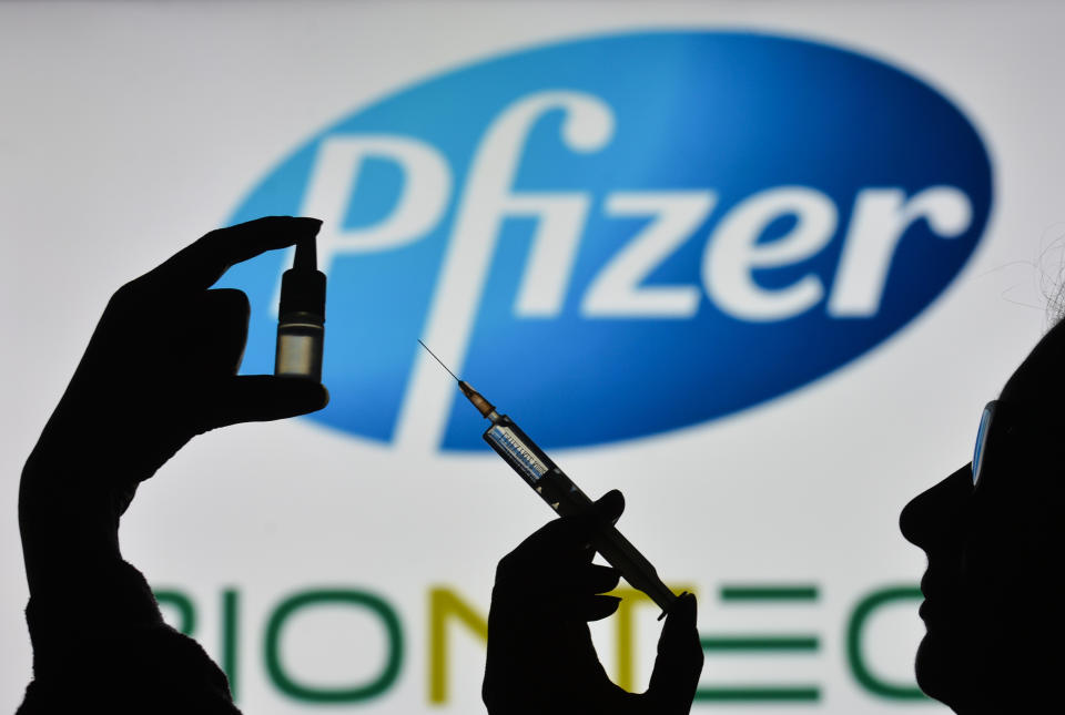 IRELAND - 2021/02/07: In this photo illustration a silhouette of a man holding a medical syringe and a vial seen displayed in front of the Pfizer logo on a screen. (Photo Illustration by Cezary Kowalski/SOPA Images/LightRocket via Getty Images)
