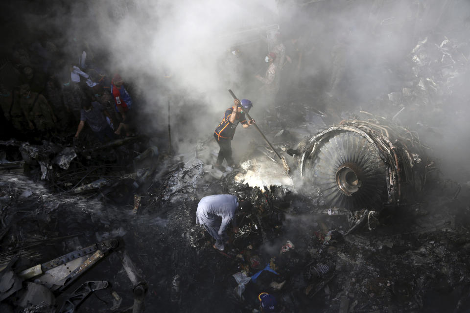 Volunteers look for survivors of a plane that crashed in a residential area of Karachi, Pakistan, May 22, 2020. An aviation official says a passenger plane belonging to state-run Pakistan International Airlines carrying more than 100 passengers and crew has crashed near the southern port city of Karachi. (AP Photo/Fareed Khan)