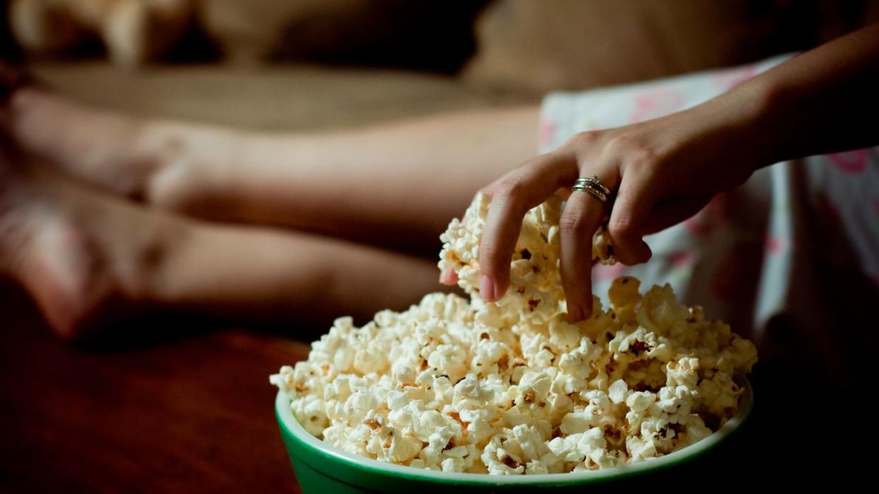 woman hand into bowl of popcorn