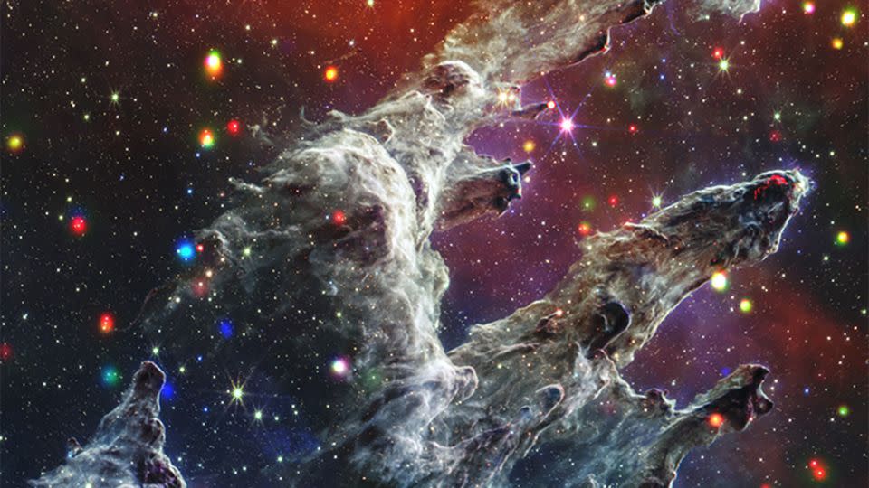 Los Pilares de la Creación representan una región de formación estelar donde altas columnas de polvo oscuro crean una guardería estelar. Los puntos de colores que recorren la imagen representan estrellas jóvenes que brillan en rayos X y luz infrarroja. - Observatorio de rayos X Chandra/NASA