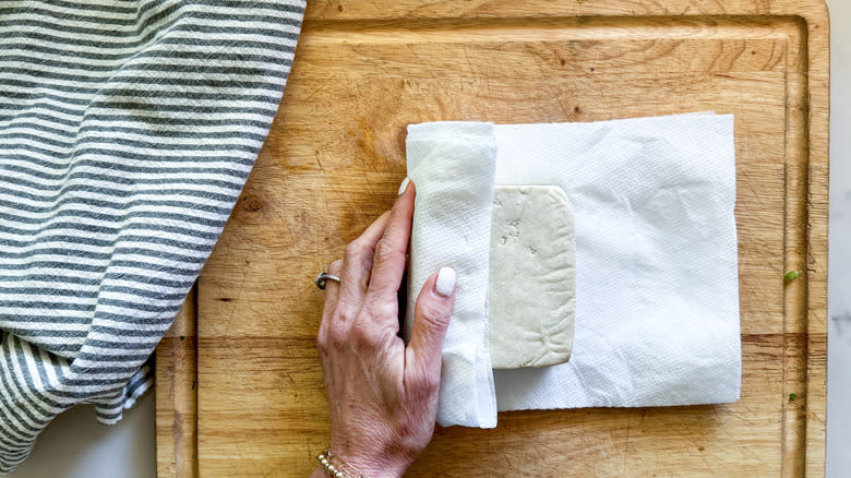 hand wrapping tofu in paper towel