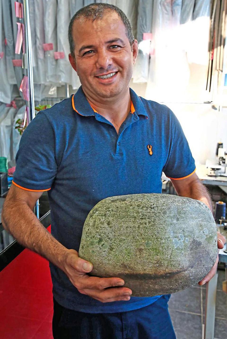 Hemen Osman with the boulder that shattered the glass in the door at his dry cleaning business (Nigel Howard)