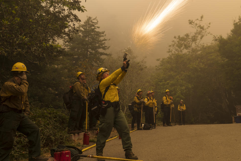 A firefighter shoots an incendiary device during a back burn to help control the Dolan Fire at Limekiln State Park in Big Sur, Calif,. Friday, Sept. 11, 2020. (AP Photo/Nic Coury)